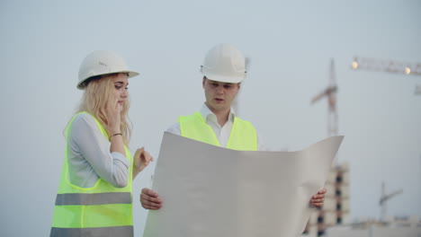 Two-engineers-discuss-looking-at-the-drawings-of-the-construction-plan-and-the-location-of-the-objects-specifying-the-contractor-on-the-phone-details.-Talking-on-the-phone-at-the-construction-site.
