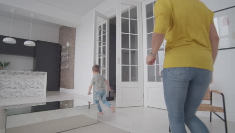 mom-and-son-have-fun-playing-catch-up-at-home-in-a-white-interior.-Run-around-the-house-with-your-child-and-play-hide-and-seek