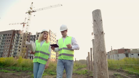 Construction-Manager-And-Engineer-walk-Working-On-Building-Site-using-tablet-and-print.