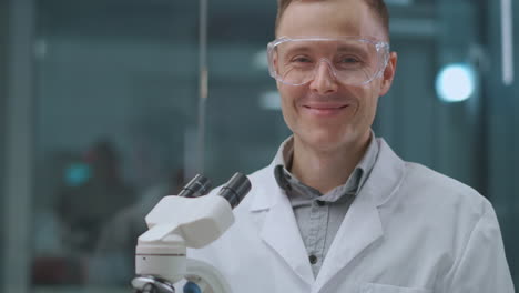 smiling-male-lab-assistant-in-laboratory-looking-at-camera-scientist-and-forensic-expert-portrait-of-specialist
