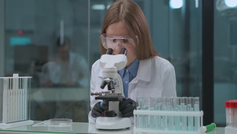 La-Mujer-Microbióloga-Está-Explorando-Muestras-En-El-Laboratorio-Mirando-Al-Microscopio-Especialista-Del-Laboratorio-Médico-De-Análisis-De-ADN-En-La-Universidad-De-Virología.