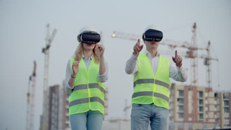 Zwei-Inspektoren-Der-Zukunft-Auf-Der-Baustelle-Verwenden-Virtual-Reality-Brillen-Vor-Dem-Hintergrund-Von-Gebäuden-Und-Kränen