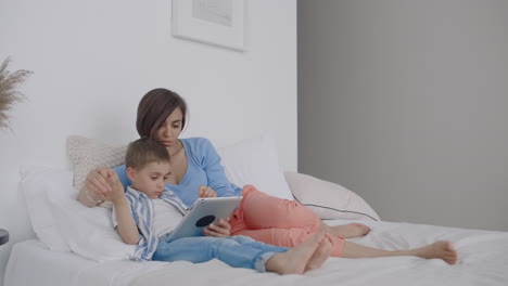 Happy-family-mother-and-child-son-with-tablet-in-evening.-Happy-family-mother-and-child-son-with-tablet-in-evening-before-bed