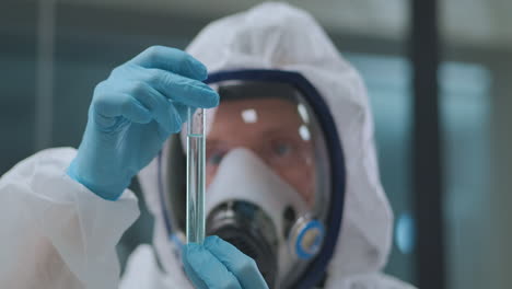 chemist-is-working-with-dangerous-chemicals-in-laboratory-scientist-is-dressed-protective-gown-and-mask-closeup-of-face-and-test-tube