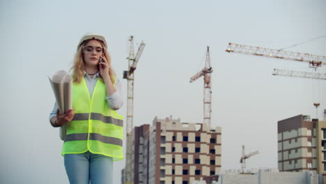 Dialogue-on-the-phone-a-woman-in-a-helmet-on-the-background-of-construction-discusses-with-the-Director-of-the-construction-site-of-the-building.