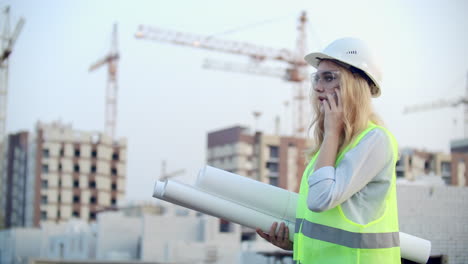 Dialogue-on-the-phone-a-woman-in-a-helmet-on-the-background-of-construction-discusses-with-the-Director-of-the-construction-site-of-the-building.