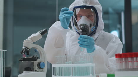 male-scientist-is-working-with-dangerous-and-toxic-chemicals-in-chemical-laboratory-using-protective-dress-mask-and-gloves-researching-by-microscope