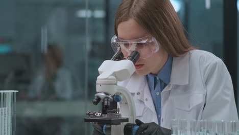 forensic-expert-is-testing-evidence-in-laboratory-viewing-samples-in-microscope-female-technician-is-researching-analysis-portrait-of-woman-in-lab