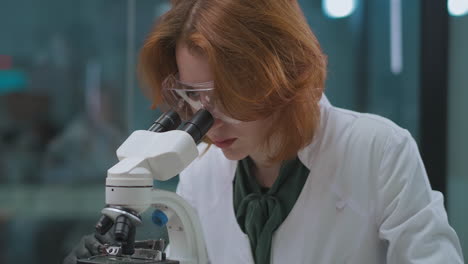 La-Mujer-Biotecnóloga-Está-Trabajando-En-Un-Laboratorio-De-Investigación-Viendo-Muestras-En-Un-Retrato-De-Microscopio-De-Una-Persona-Experta-Que-Explora-Virus-Y-Bacterias.