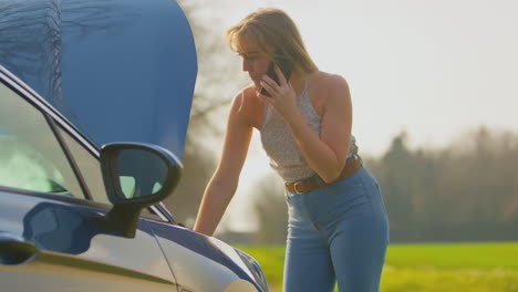 Frustrated-Woman-With-Broken-Down-Car-On-Country-Road-Calling-For-Help-On-Mobile-Phone