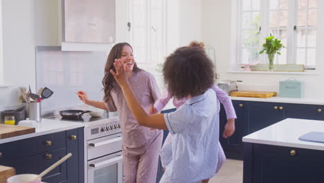 Pregnant-Family-With-Two-Mums-Dancing-Making-Morning-Pancakes-In-Kitchen-With-Daughter