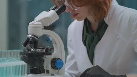 La-Científica-Femenina-Está-Explorando-Muestras-En-El-Microscopio-En-El-Laboratorio,-Experiencia-Química-O-Microbiológica,-Detalles-De-La-Persona-Y-El-Equipo.