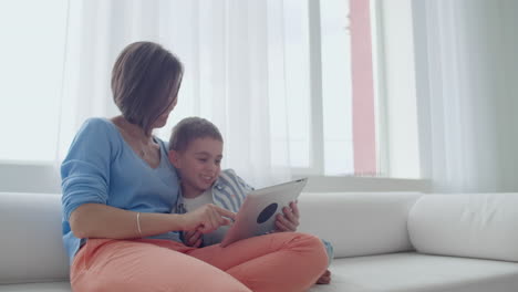 Mother-and-son-playing-with-digital-tablet-at-home.-Young-mother-with-her-5-years-old-smiling-with-digital-tablet-at-home