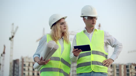 Construction-Manager-And-Engineer-walk-Working-On-Building-Site-using-tablet-and-print.