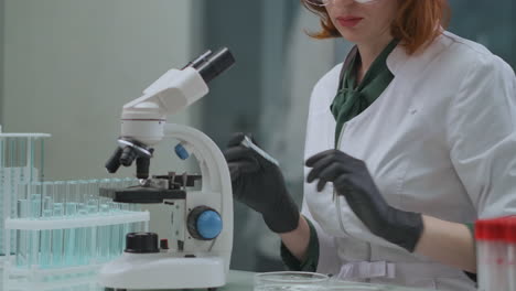 Una-Técnica-Femenina-Está-Investigando-Análisis-En-Laboratorio-Utilizando-Tubos-De-Ensayo-Con-Líquidos-Y-Control-De-Calidad-De-Microscopio-En-Producción-Y-Experiencia-Ecológica