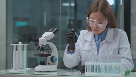 Una-Joven-De-Laboratorio-De-Estudiantes-De-Medicina-Está-Trabajando-Con-Tubos-De-Ensayo-Con-Productos-Químicos-Y-Análisis-Médicos-Haciendo-Portaobjetos-De-Microscopio-Para-Investigación-Y-Exploración.