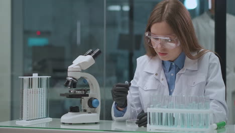 La-Mujer-Técnica-De-La-Sala-De-Laboratorio-Químico-Está-Probando-La-Sustancia-Que-Se-Aplica-En-La-Placa-Para-Investigar-En-Microscopio-Estudiante-Médico-O-Químico