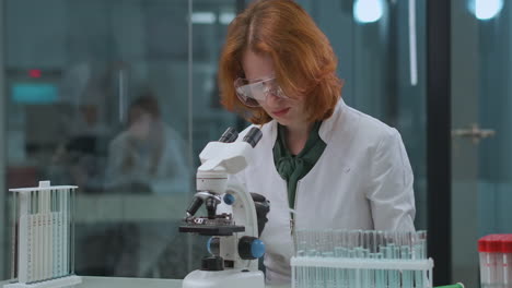 female-doctor-is-exploring-analysis-in-laboratory-taking-sample-of-liquid-from-test-tube-and-looking-in-microscope-health-professional-woman-in-clinic-of-coronavirus