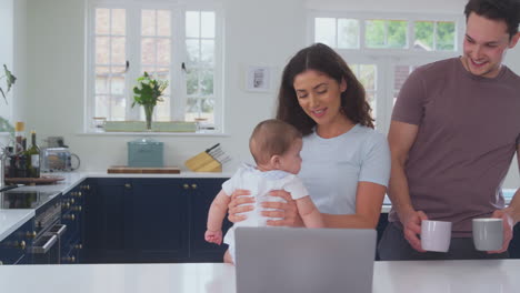 Loving-Transgender-Family-With-Baby-At-Home-Together-With-Laptop-Drinking-Coffee-At-Kitchen-Counter