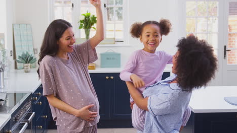 Familia-Embarazada-Con-Dos-Mamás-Bailando-Haciendo-Panqueques-Matutinos-En-La-Cocina-Con-Su-Hija