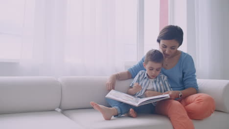 Happy-mother-and-child-son-reading-book-laughing-in-bed.-Happy-family-mother-and-child-son-reading-holding-book-lying-in-bed-smiling-mom-baby-sitter