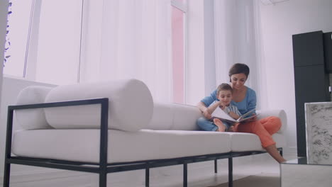 Mother-and-son-read-books.-Happy-young-mother-and-son-read-books-on-the-sofa-at-home