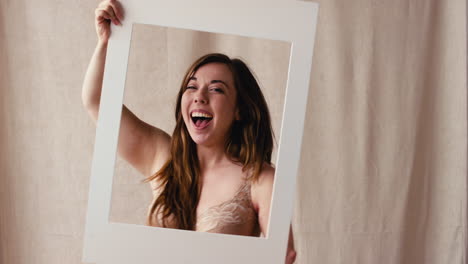 Studio-Shot-Of-Confident-Woman-With-Disabled-Arm-In-Underwear-Looking-Through-Picture-Frame
