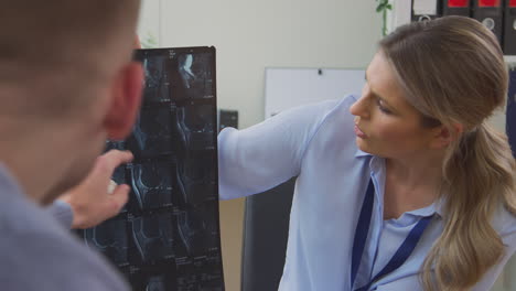 Woman-Doctor-Or-GP-In-Office-With-Male-Patient-Looking-At-CT-Or-MRI-Scan