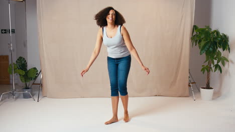 Studioporträtaufnahme-Einer-Lässig-Gekleideten,-Körperbewussten-Frau,-Die-In-Die-Luft-Springt