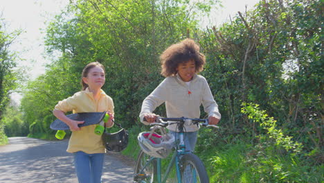 Junge-Mit-Fahrrad-Und-Mädchen-Mit-Skateboard-Gehen-Gemeinsam-Die-Landstraße-Entlang