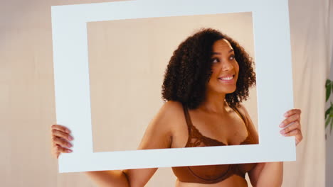 Studio-Shot-Of-Confident-Natural-Woman-In-Underwear-Making-Funny-Faces-In-Picture-Frame