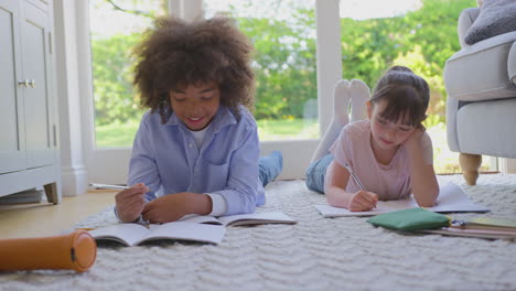 Junge-Und-Mädchen-Liegen-Zu-Hause-Auf-Dem-Teppich-Im-Wohnzimmer-Und-Machen-Gemeinsam-Schulhausaufgaben