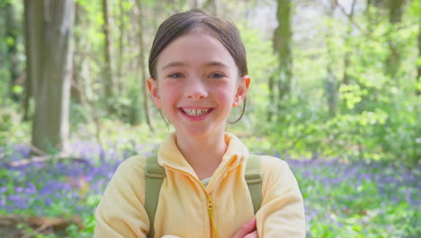 Portrait-Of-Smiling-Girl-Walking-In-Spring-Woodlands-With-Bluebells