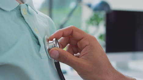 Close-Up-Of-Male-Doctor-Or-GP-Wearing-White-Coat-Examining-Boy-Listening-To-Chest-With-Stethoscope
