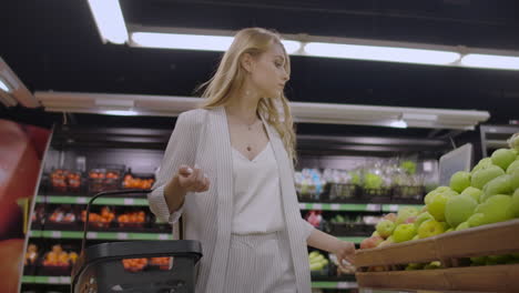 Una-Hermosa-Mujer-Camina-Por-El-Supermercado-Con-Una-Canasta-En-Las-Manos-Mirando-Los-Estantes-De-Frutas.-Comprar-Frutas-Y-Verduras-Frescas.
