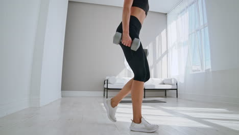 A-woman-at-home-on-a-Sunny-day-in-the-living-room-lunges-back-with-dumbbells-in-her-hands.-Healthy-lifestyle-daily-exercise-at-home.