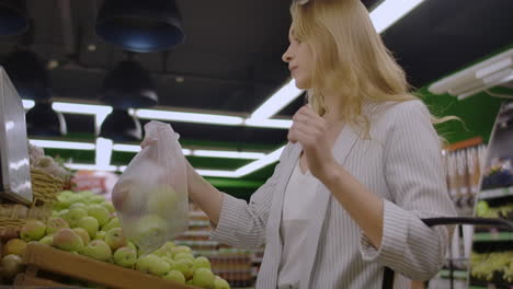 Young-Woman-Weighing-Apples-on-the-Electronic-Scales.-Housewife-Shopping-in-a-Supermarket-in-the-Department-of-Fruit-and-Vegetables.-Slow-Motion.-Sale-Shopping-Consumerism-and-People-Concept