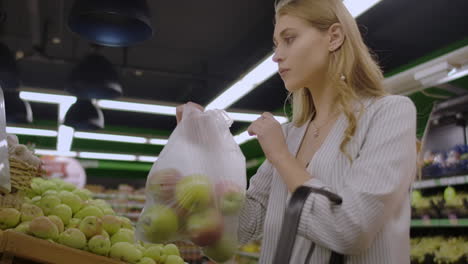 Middle-aged-woman-weighs-a-bag-of-apples-in-the-supermarket