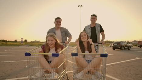 Young-friends-having-fun-on-a-shopping-carts.-Multiethnic-young-people-playing-with-shopping-cart