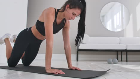 Young-sexy-brunette-woman-in-sportswear-doing-side-plank-exercise-shifts-hands-while-kneeling-in-white-beautiful-apartment-interior
