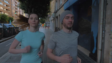 A-young-couple-jogging-on-a-paved-sidewalk