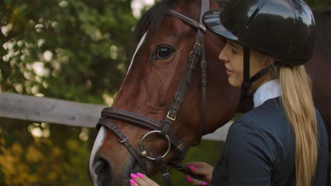 Female-is-enjoying-her-time-with-a-horse-before-training.-She-is-stroking-the-horse-and-sharing-her-good-mood-and-whisper-something-to-the-friend