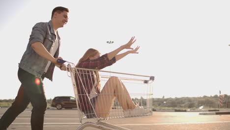 Young-friends-having-fun-on-shopping-trolleys.-Multiethnic-young-people-racing-on-shopping-cart.-slow-motion