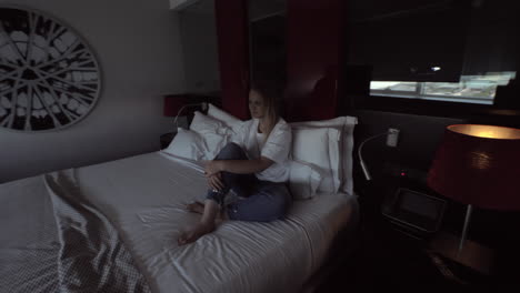 Woman-sitting-in-a-hotel-room-and-turning-on-the-automatic-window-opening-system