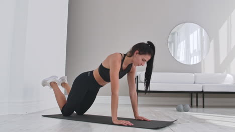 Young-sexy-brunette-woman-in-sportswear-doing-side-plank-exercise-shifts-hands-while-kneeling-in-white-beautiful-apartment-interior
