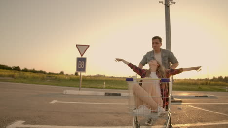 Cheerful-people-a-couple-a-man-and-a-woman-at-sunset-ride-on-supermarket-trolleys-in-slow-motion.
