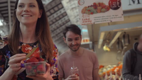 A-couple-buying-a-box-of-strawberries-on-a-market