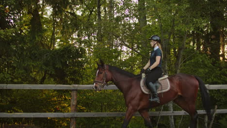 Professional-horsewomen-is-riding-on-her-horse-in-the-horse-club-next-to-the-forest.-They-are-enjoying-beatifull-morning-on-the-nature