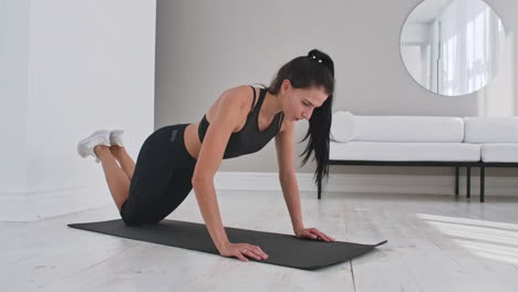 Young-sexy-brunette-woman-in-sportswear-performs-pushups-kneeling-at-home-on-a-rug