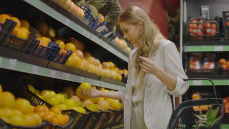 Woman-hand-choosing-lemons-at-the-grocery-store-picks-up-lemons-at-the-fruit-and-vegetable-aisle-in-a-supermarket